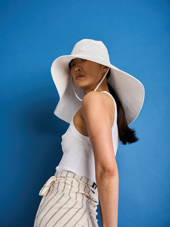 The Lucie Marquis 'Dylan Sunhat' is a wide brimmed sun hat made from high quality cotton twill with heavy topstitching and a wooden block cord end. Inspired by the iconic spirit of Bob Dylan and the bold essence of Georgia O'Keeffe, the sun hat embodies timeless style with a subtle nod to the 70s and a touch of cowboy charm. Perfect for shielding from the sun, it's the ideal accessory for your travel adventures.