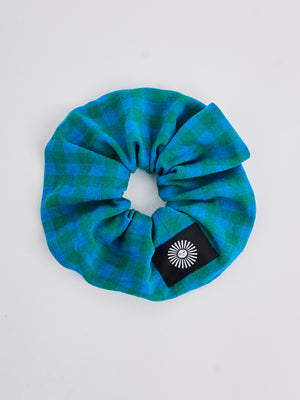 The Lucie Marquis 'Susie Scrunchie' is a stylish oversized hair scrunchie made from leftover fabric scraps. The scrunchie is 7cm wide and designed to wrap around twice. It features a brand label stitched flat on one side. The scrunchie effortlessly elevates any outfit. A great travel accessory, sustainably made.